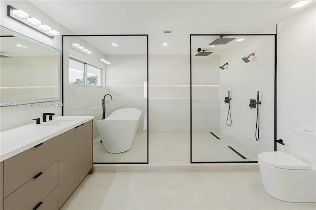 bathroom with tile walls, a freestanding bath, toilet, vanity, and a walk in shower