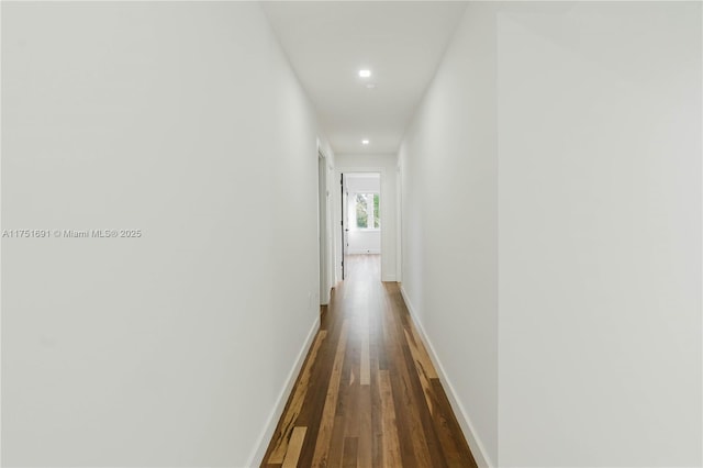 hallway with dark wood-style flooring and baseboards