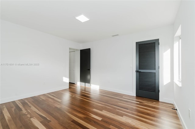 empty room featuring baseboards, visible vents, and wood finished floors