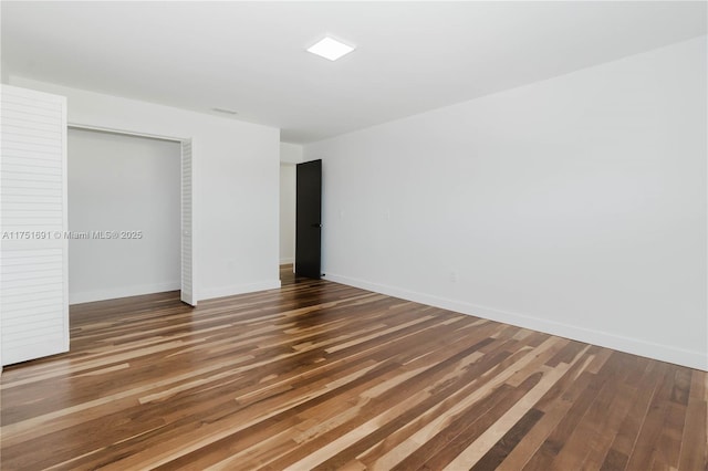 unfurnished bedroom featuring dark wood-style floors, a closet, and baseboards