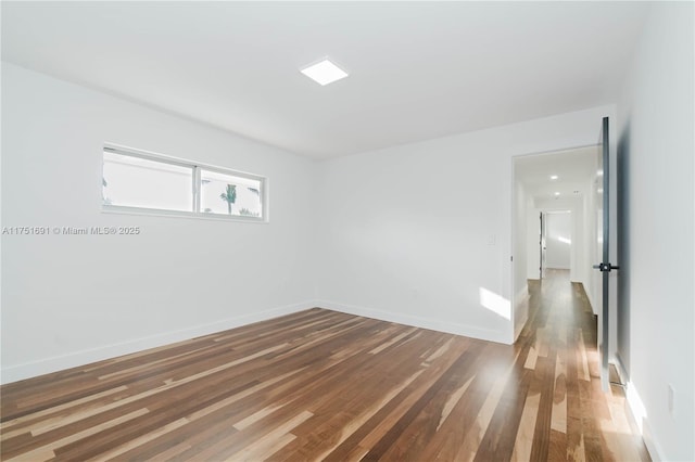 empty room with dark wood finished floors and baseboards