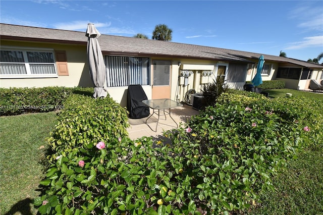 back of house with a patio, a lawn, and stucco siding