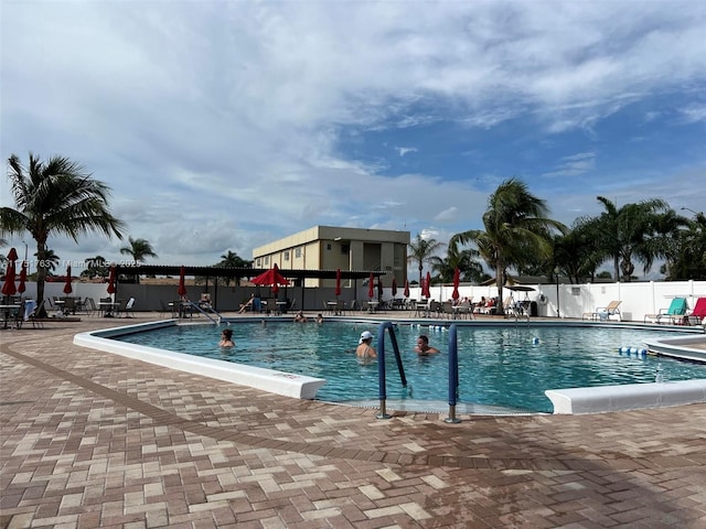 community pool with a patio area and fence