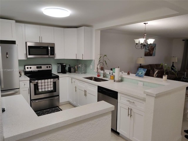 500 NE 12th Ave Unit 102, Hallandale Beach, FL 33009 - kitchen featuring stainless steel appliances, a peninsula, a sink, white cabinets, and decorative light fixtures