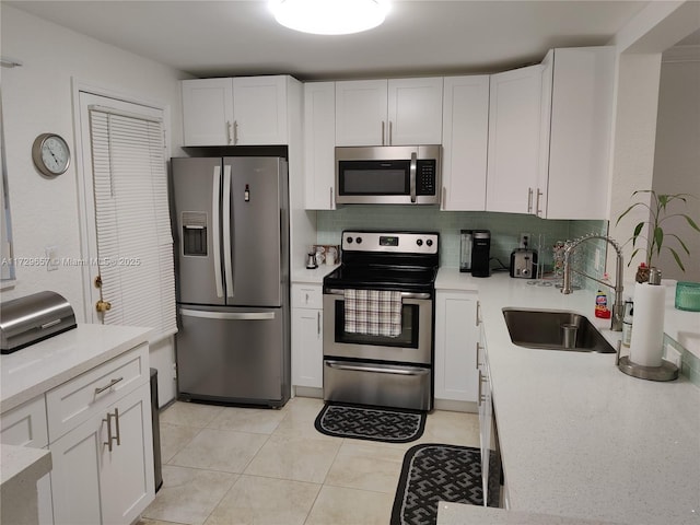 kitchen with appliances with stainless steel finishes, white cabinets, and a sink