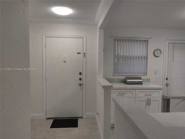 entrance foyer with crown molding, light tile patterned floors, a textured wall, a textured ceiling, and baseboards