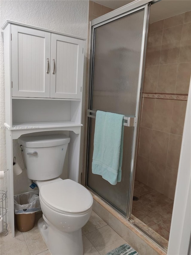 bathroom featuring a shower stall, toilet, and tile patterned floors