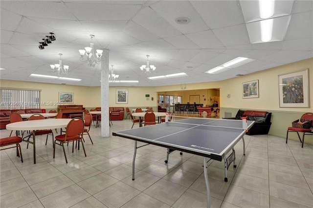 playroom with a drop ceiling, a notable chandelier, and light tile patterned floors