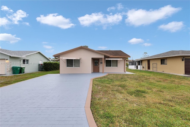 single story home featuring decorative driveway, a front lawn, and stucco siding