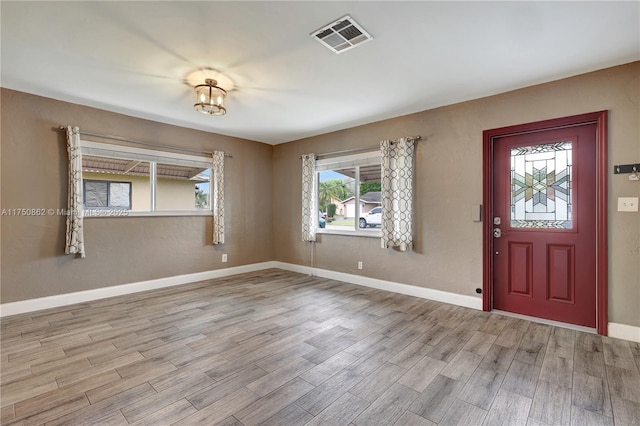 foyer entrance with light wood-type flooring, visible vents, and baseboards