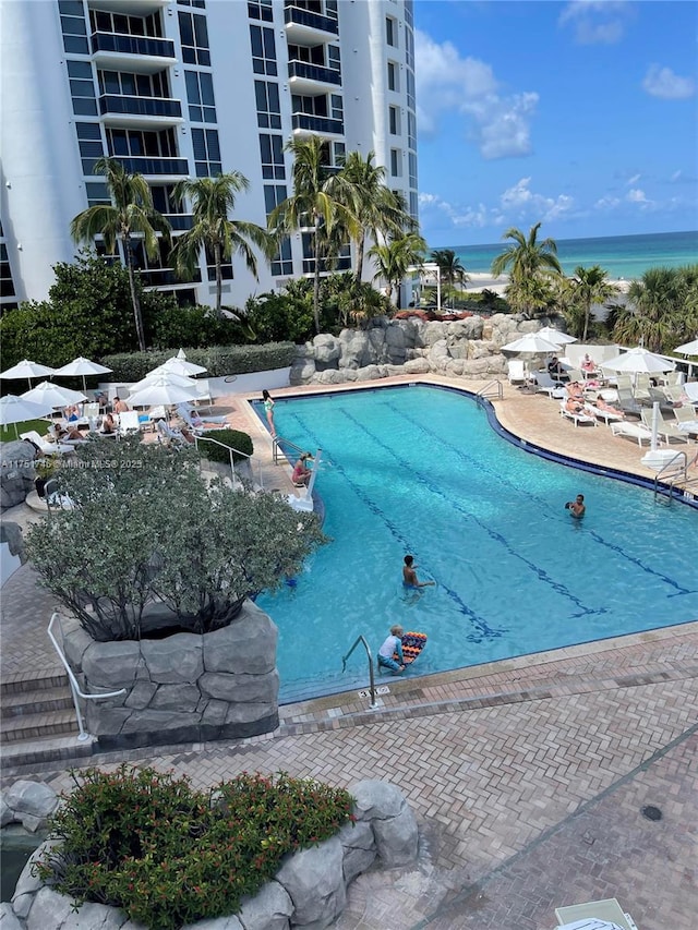 pool featuring a water view and a patio