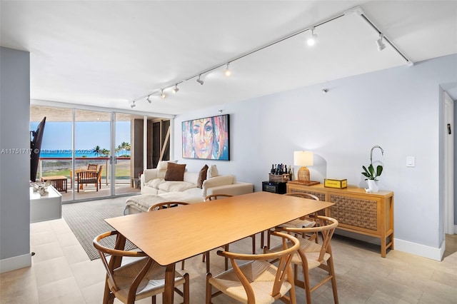 dining room featuring baseboards, rail lighting, and floor to ceiling windows