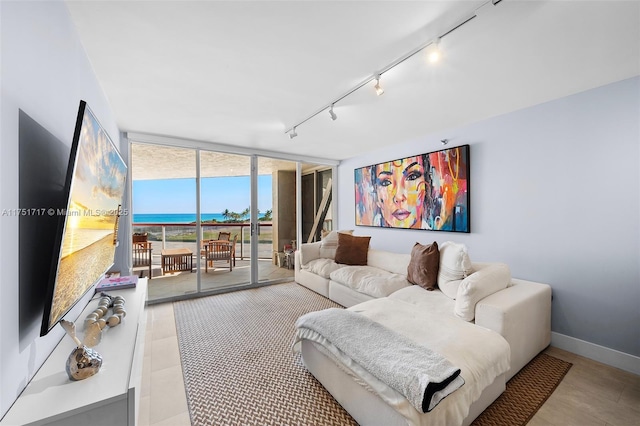 living room featuring rail lighting, floor to ceiling windows, baseboards, and light tile patterned floors