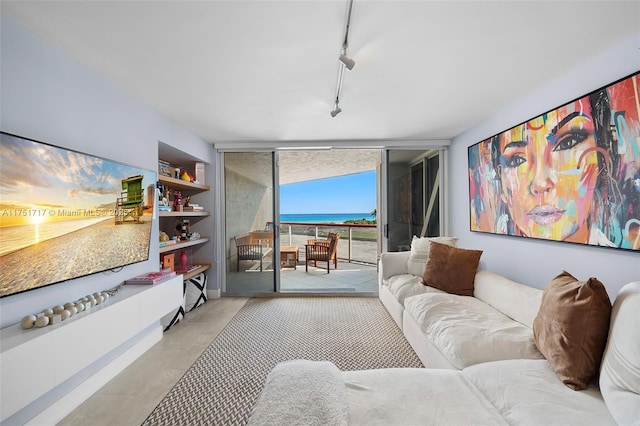 living room featuring a water view, rail lighting, and expansive windows