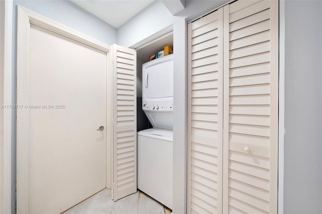 laundry area with laundry area, light tile patterned flooring, and stacked washer and clothes dryer