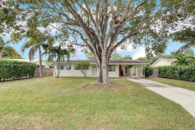 ranch-style home with an attached carport, fence, driveway, stucco siding, and a front lawn