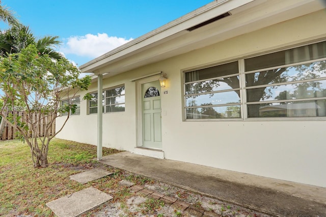 entrance to property featuring fence and stucco siding