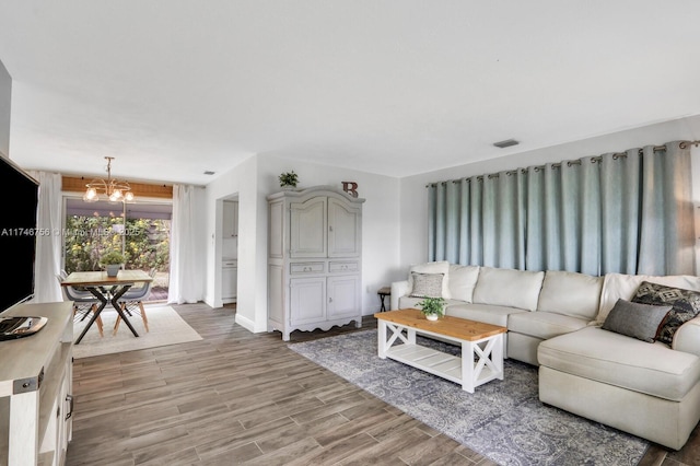 living area featuring a chandelier, visible vents, and wood finished floors