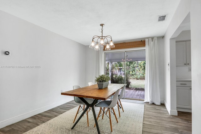 dining room featuring an inviting chandelier, wood finished floors, visible vents, and baseboards