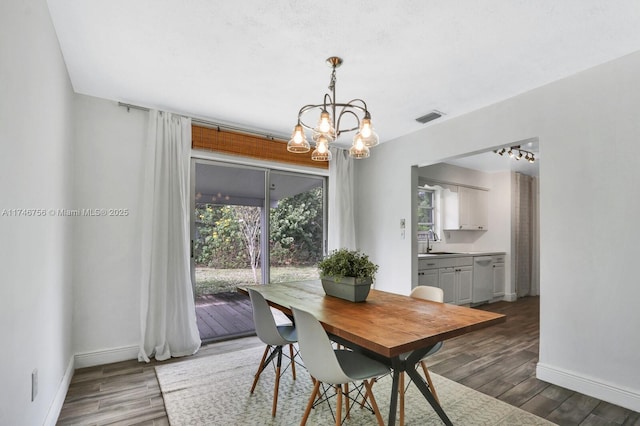 dining area with dark wood-style floors, an inviting chandelier, visible vents, and baseboards