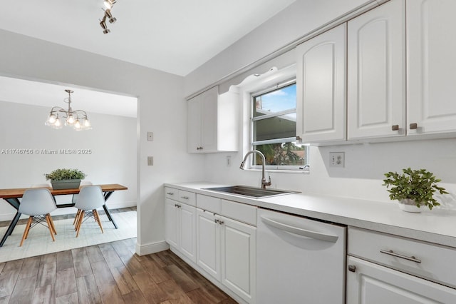 kitchen with white dishwasher, white cabinetry, light countertops, and a sink