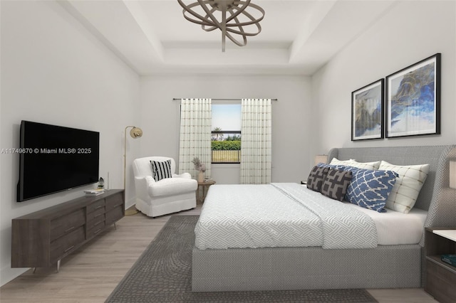 bedroom with light wood finished floors and a raised ceiling