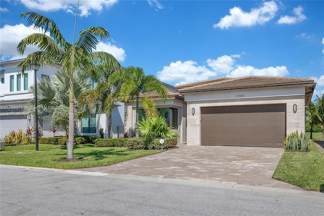 view of front of home with a front lawn, decorative driveway, and an attached garage