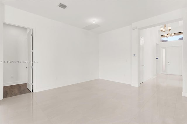 spare room with a chandelier, visible vents, and baseboards