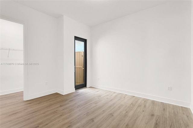 spare room featuring light wood finished floors and baseboards