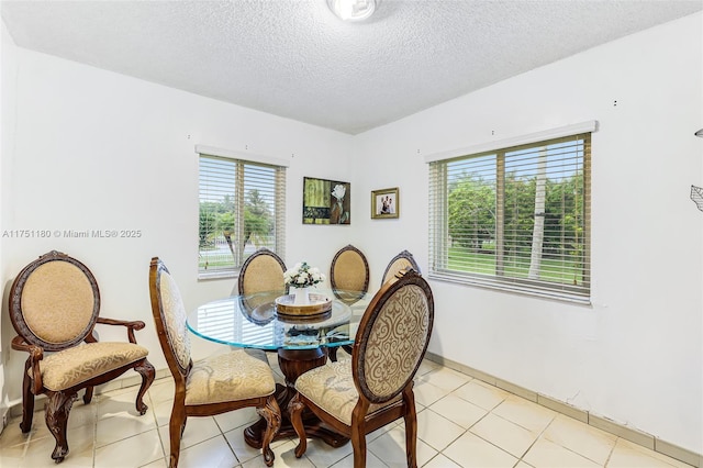 dining space with a textured ceiling and light tile patterned floors