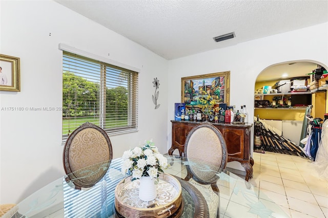 dining area with light tile patterned floors, visible vents, and a textured ceiling