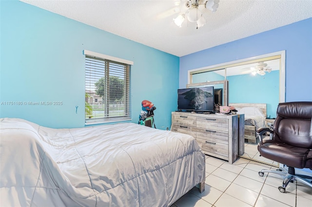 bedroom with a closet, light tile patterned flooring, ceiling fan, and a textured ceiling