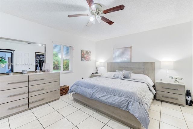 bedroom featuring light tile patterned flooring, ceiling fan, and a textured ceiling