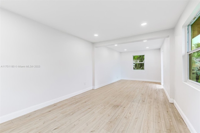 empty room with light wood-type flooring, baseboards, and recessed lighting