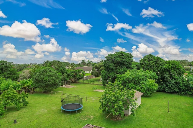 view of community featuring a trampoline, fence, and a lawn