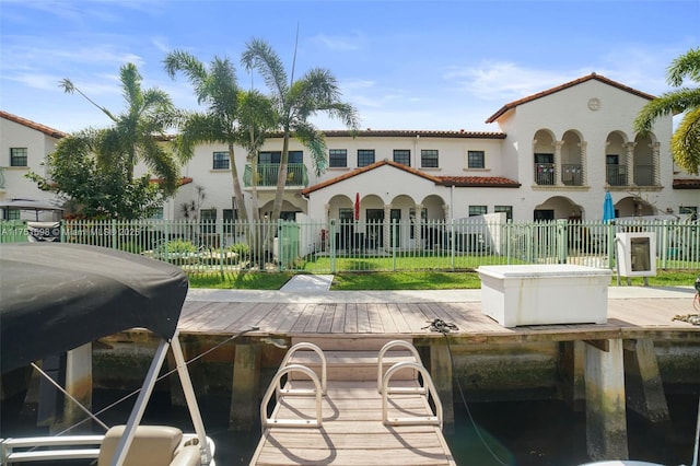 rear view of property with a tile roof, fence, and stucco siding