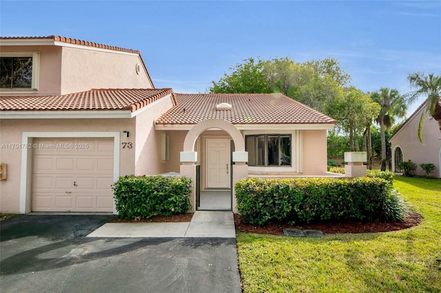 view of front facade featuring a front yard, a tile roof, an attached garage, and stucco siding