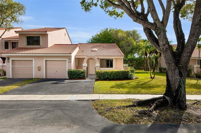 view of front of house featuring an attached garage, driveway, a tiled roof, stucco siding, and a front yard