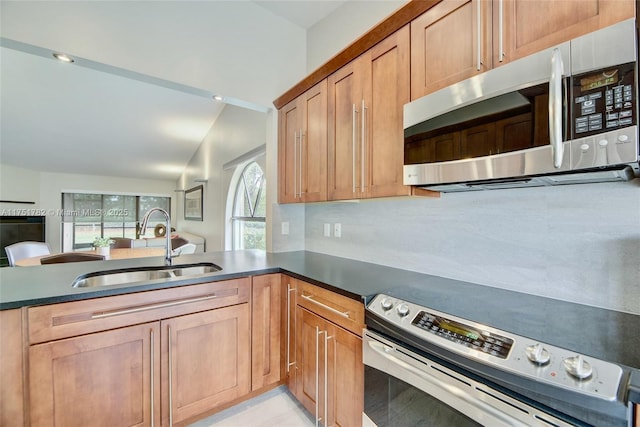 kitchen with dark countertops, appliances with stainless steel finishes, decorative backsplash, and a sink