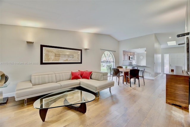 living area with lofted ceiling, light wood-style flooring, and baseboards