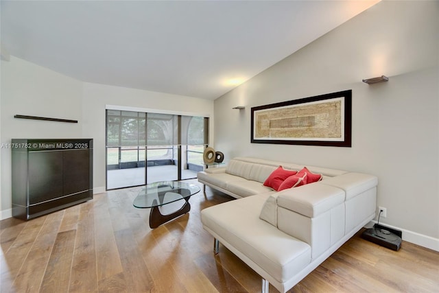 living area with light wood finished floors, baseboards, and vaulted ceiling