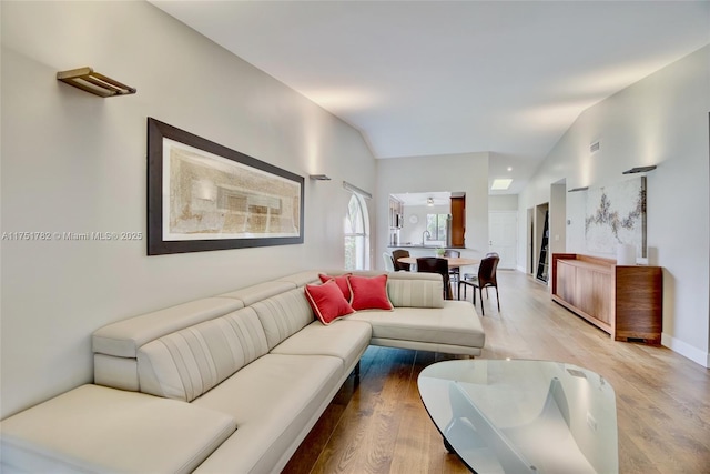 living area featuring visible vents, vaulted ceiling, and light wood-style flooring