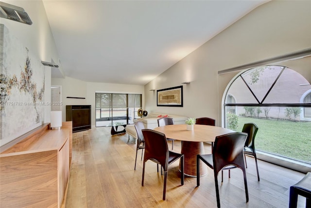 dining area featuring light wood-type flooring, high vaulted ceiling, and visible vents