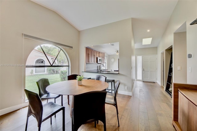 dining space featuring lofted ceiling, light wood-style flooring, and baseboards