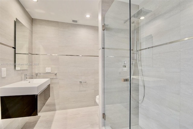 bathroom with toilet, recessed lighting, vanity, tile walls, and a stall shower