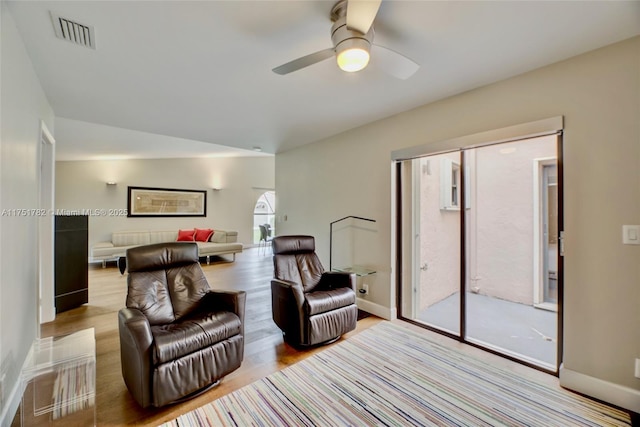 living room with a ceiling fan, baseboards, visible vents, and light wood finished floors