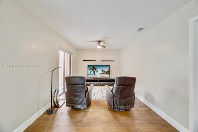 sitting room featuring a ceiling fan, visible vents, baseboards, and wood finished floors