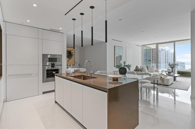 kitchen with dark countertops, modern cabinets, a sink, and white cabinetry