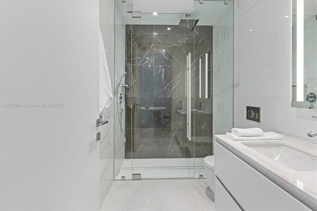 bathroom with a marble finish shower, toilet, marble finish floor, vanity, and tile walls