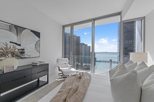 bedroom featuring expansive windows, a water view, and a city view